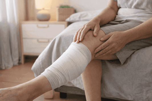 Adult sitting on a bed with a bandaged lower leg