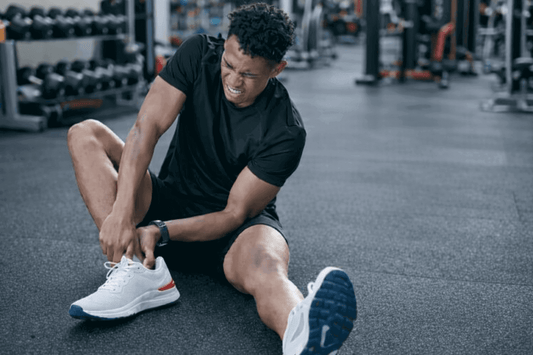 Man sitting on a gym floor holding his ankle