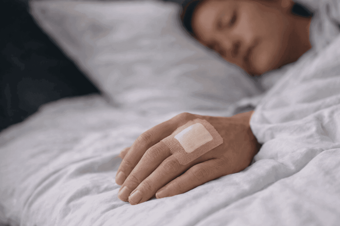 Hand with a bandage resting on bed during sleep